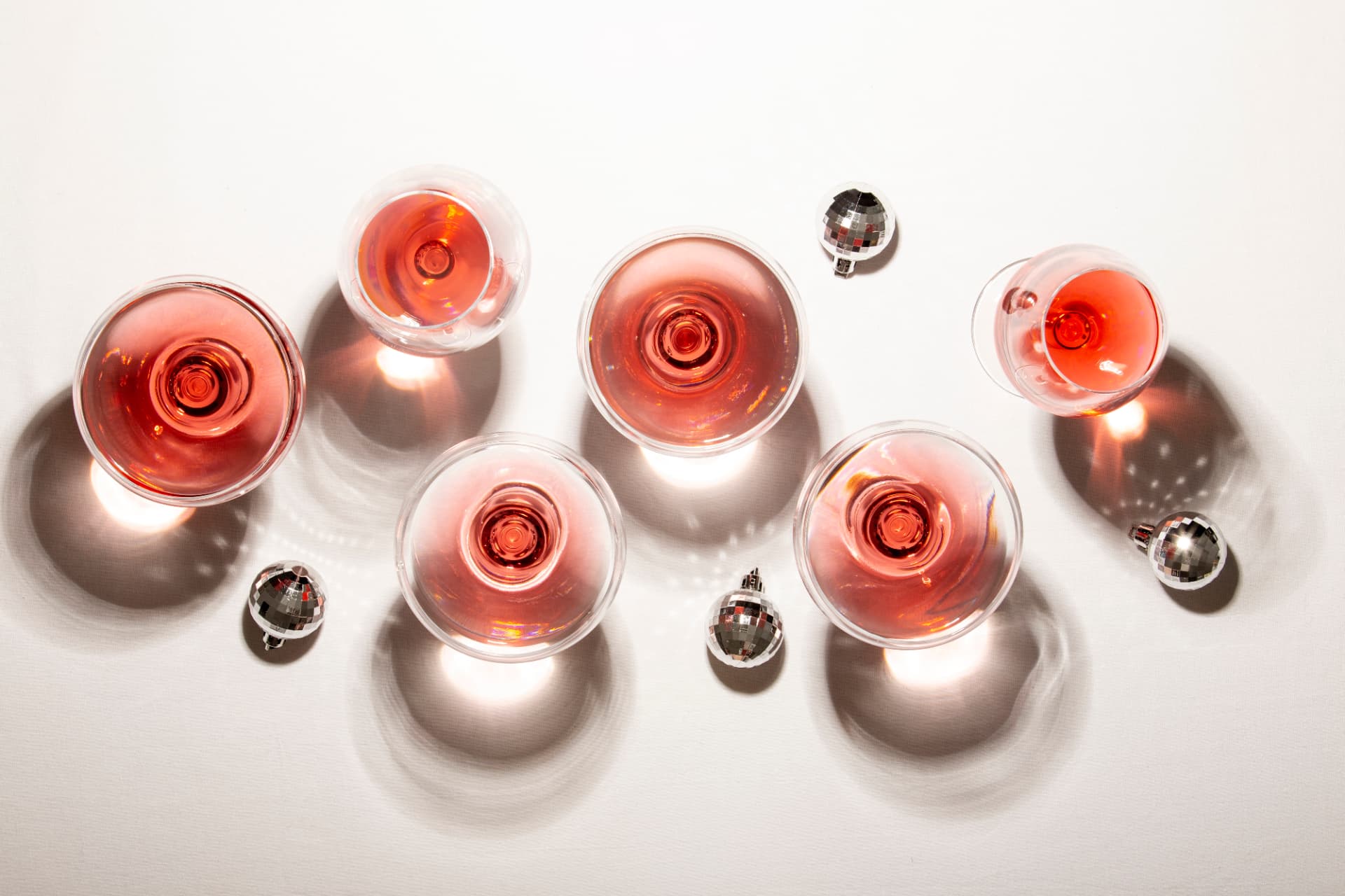 Glasses of rosé wine photographed from above on a soft white surface